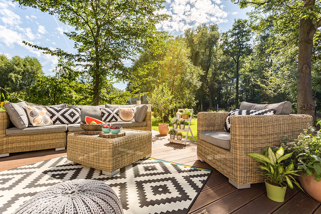 Sunny outdoor terrace with rattan furnitures in big garden